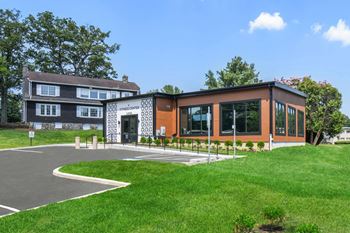 A modern building with a glass facade is situated in a grassy area.
